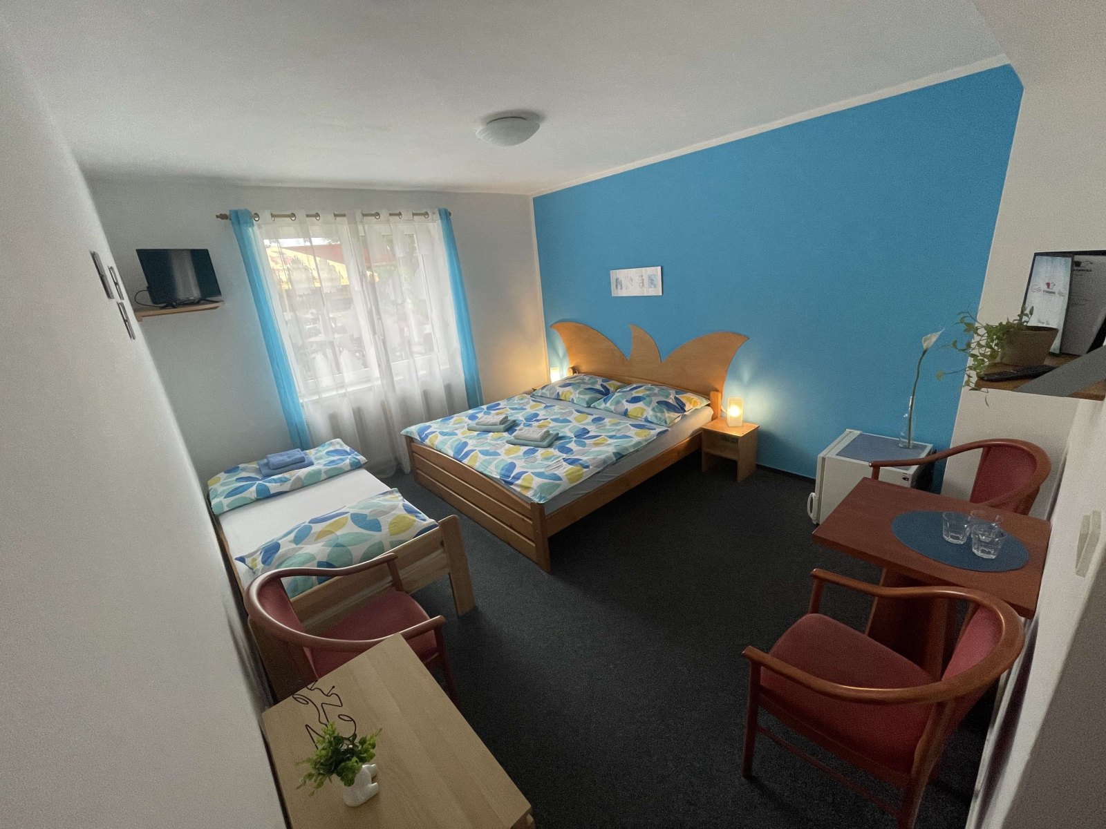 Helles Zimmer mit Holzbett und Tischchen am Fenster