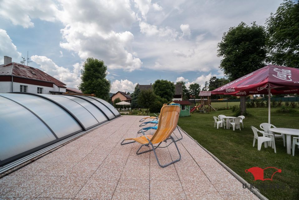 Überdachter Pool und Liegen auf der Terrasse im Garten der Pension